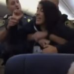 機内から警官等に無理やり降機させられる女性